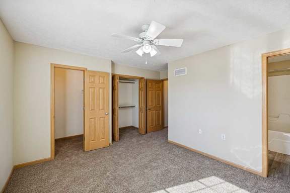 A room with a ceiling fan and carpeted floor.