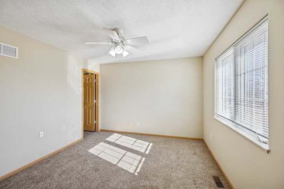 A room with a ceiling fan and a window with blinds.