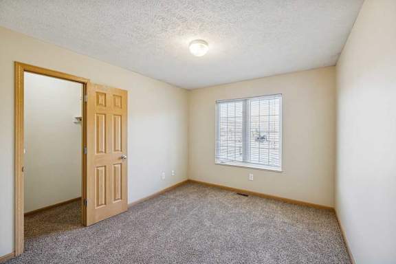 A room with a door and a window with blinds.