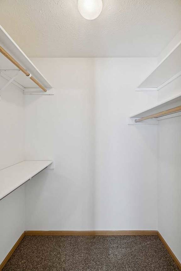 A white wall with a brown carpet and a white shelf.