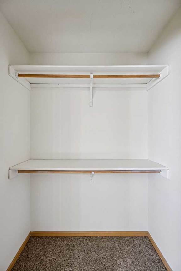 A white wall with a shelf and a hanging rod.