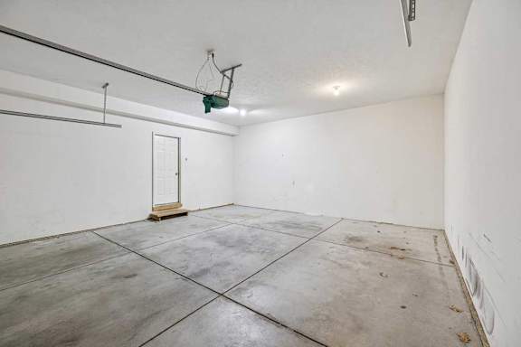 A basketball hoop is mounted on a wall in a large, empty room with concrete flooring.