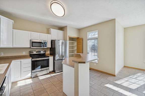 A kitchen with white cabinets and a black fridge.
