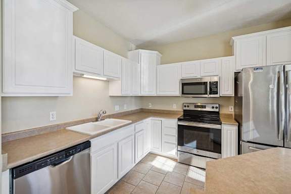 A kitchen with white cabinets and appliances.