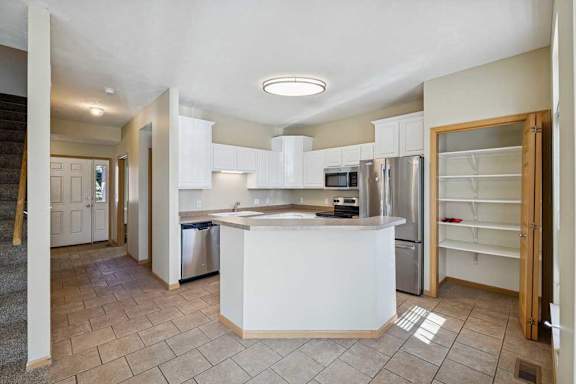 A kitchen with white cabinets and a refrigerator.