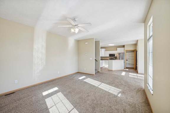 A spacious room with a ceiling fan and carpeted floor.