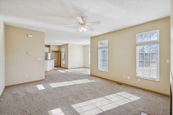 A spacious room with a carpeted floor and a ceiling fan.