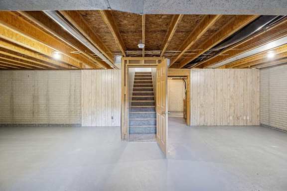 A spacious attic room with wooden beams and a central staircase.