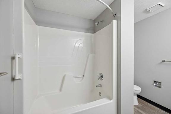 A white bathroom with a walk in shower and toilet.