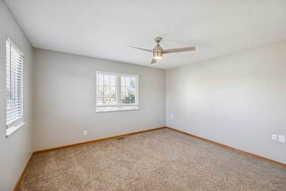A room with a ceiling fan and carpeted floor.