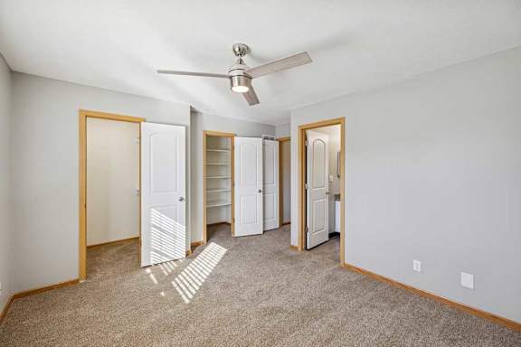 A room with a ceiling fan and three white doors.