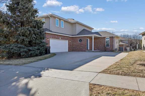 A two-story house with a garage is surrounded by a well-maintained lawn and a sidewalk.