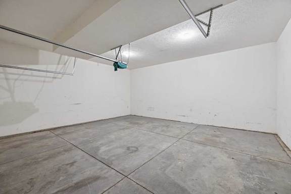 A room with a white wall and grey floor tiles.