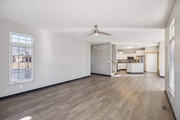 A spacious room with a ceiling fan and wooden flooring.