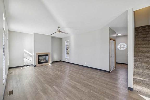 A spacious living room with a fireplace and a staircase.