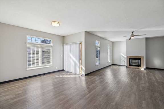 A spacious room with a fireplace and a ceiling fan.