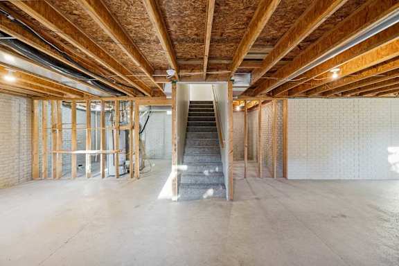 A spacious interior of a building under construction with exposed wooden beams and unfinished walls.