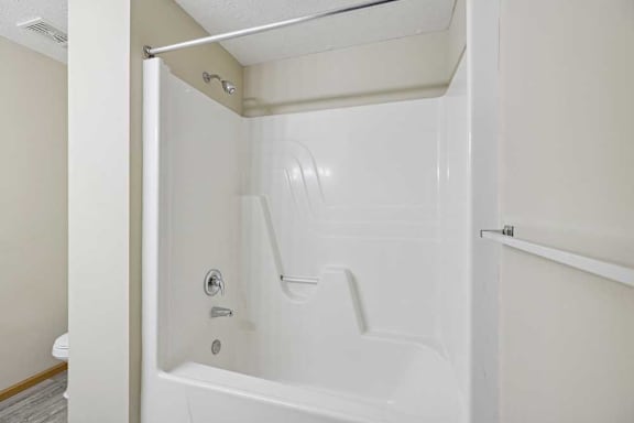 A white bathtub with a shower head and faucet.