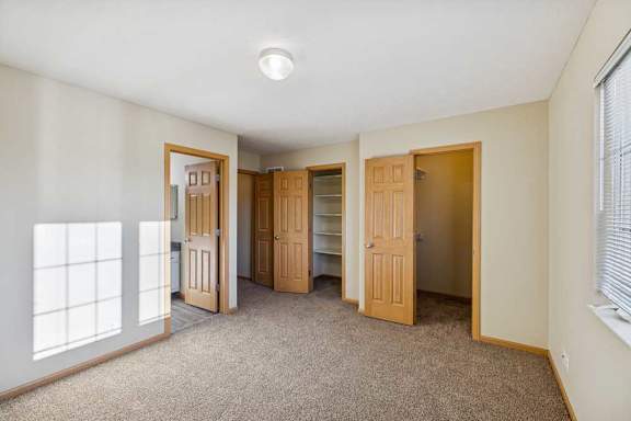A room with carpeted floor and four doors.