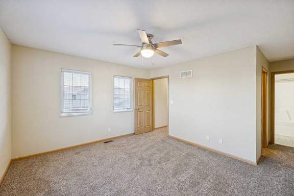A room with a ceiling fan and carpeted floor.