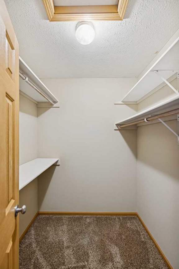 A small, empty room with a carpeted floor and a wooden door.