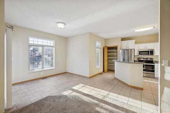A spacious living room with a kitchen area in the background.