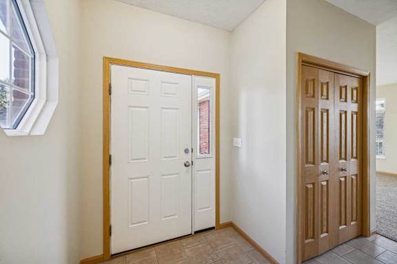 A white door with a window above it and a brown door to the right.