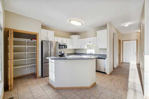 A kitchen with a white island and stainless steel appliances.
