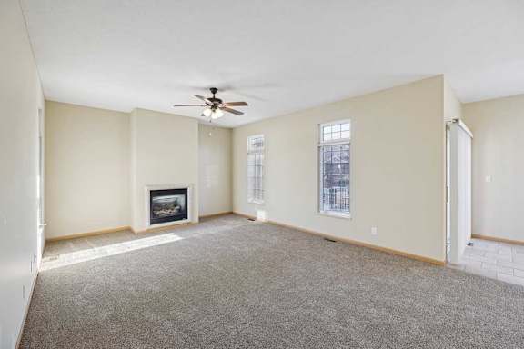 A living room with a fireplace and a ceiling fan.