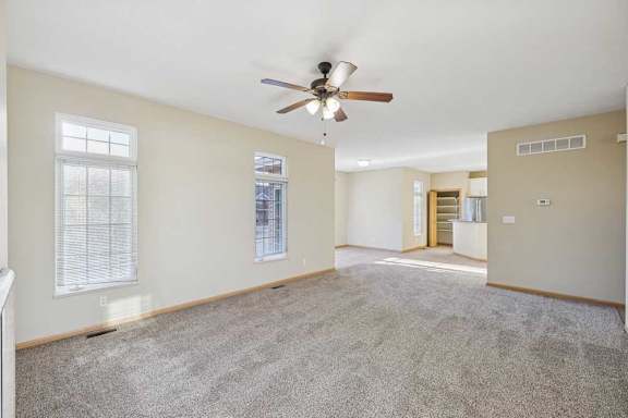 A spacious room with a ceiling fan and carpeted floor.