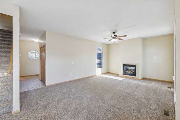 A spacious living room with a fireplace and a ceiling fan.