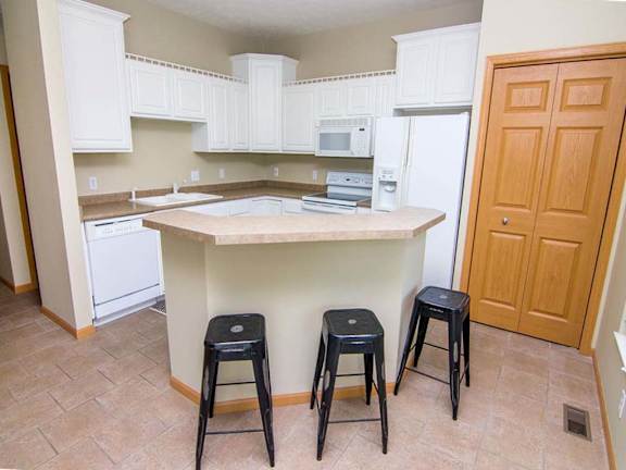 a kitchen with white cabinets, an island, and three stools
