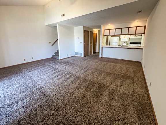a large living room with a carpeted floor and a staircase leading to another level