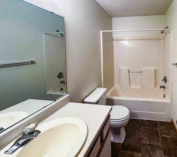 a bathroom with a white vanity sink and a combination shower and tub