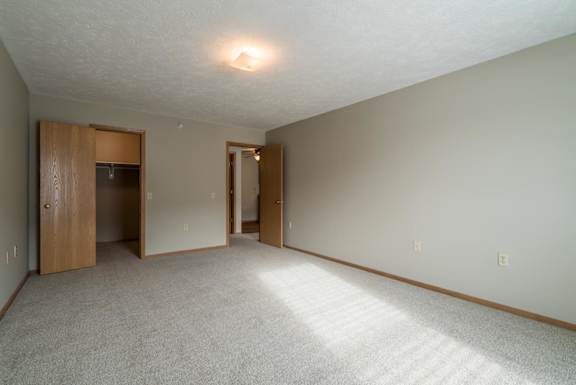 A bedroom with a carpeted floor and a ceiling light.