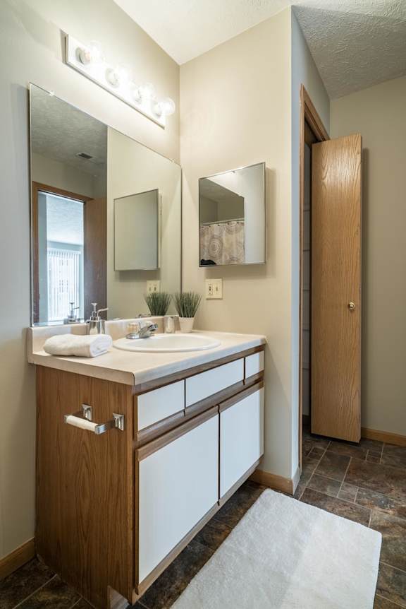 A bathroom with a sink, mirror, and lighting fixture.