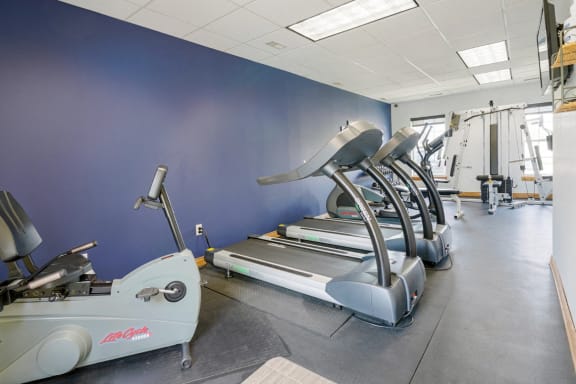 24-hour fitness center with a row of treadmills and other exercise equipment