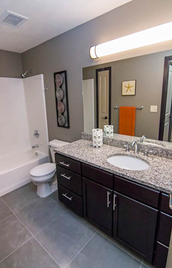 A bathroom with a toilet, sink, and a mirror.