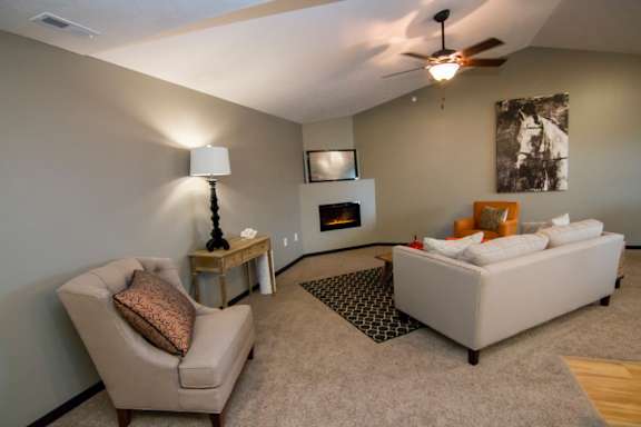 A living room with a beige couch, a chair, a lamp, a fireplace, and a fireplace