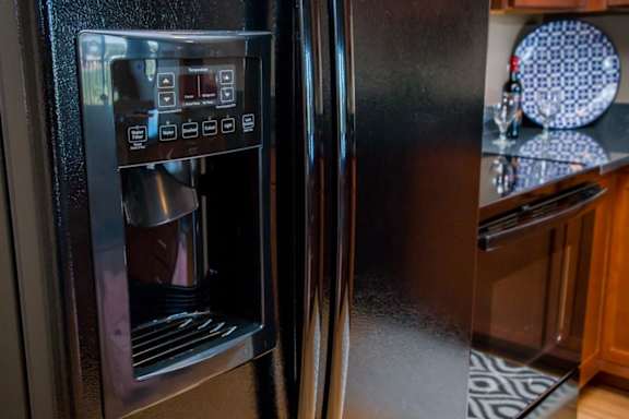 A black refrigerator with a water and ice dispenser on the left side.
