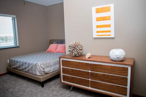 A bedroom with a bed, dresser, and a picture on the wall.
