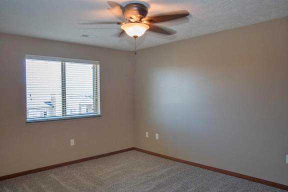 A room with a ceiling fan and a window with blinds.