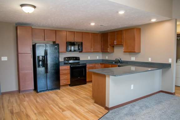 A kitchen with wooden floors and a black refrigerator.