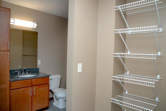 A bathroom with a toilet, sink, and shelving.