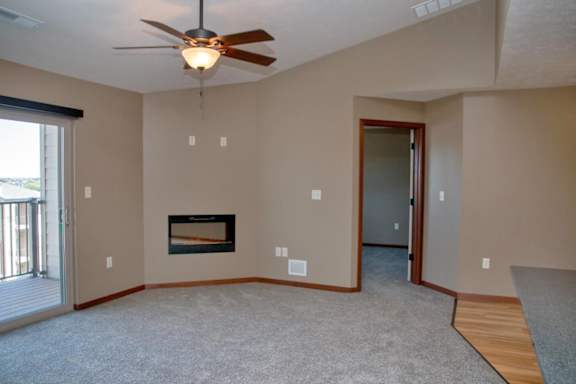 A living room with a fireplace and a ceiling fan.