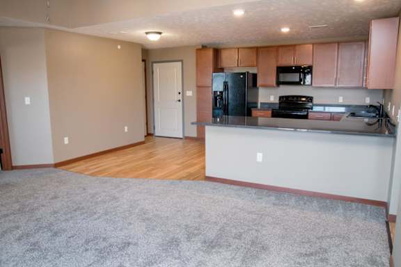 A kitchen with a refrigerator, microwave, and stove, plus a peninsula for seating