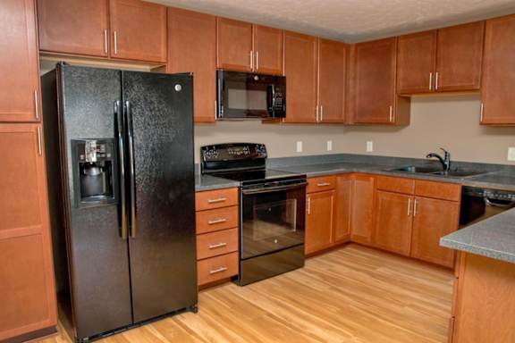 U shaped kitchen with black appliances and warm brown cabinets