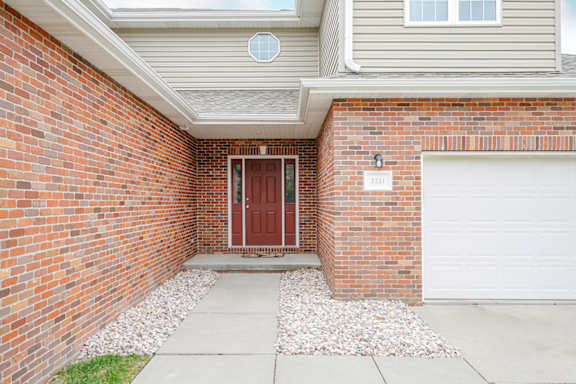 A red door is on the left side of a white garage door.