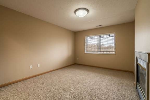an empty bedroom with a window and carpet