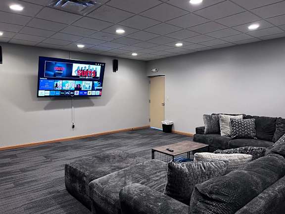 a theater room with a grey couch and a television on the wall